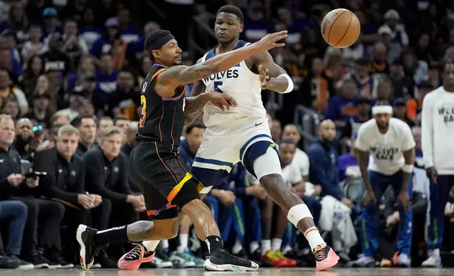 Phoenix Suns guard Bradley Beal passes around Minnesota Timberwolves guard Anthony Edwards, right, during the first half of Game 3 of an NBA basketball first-round playoff series, Friday, April 26, 2024, in Phoenix. (AP Photo/Matt York)