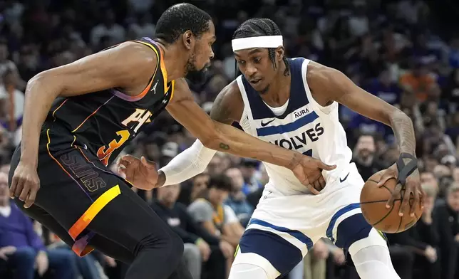 Minnesota Timberwolves forward Jaden McDaniels, right, tries to get past Phoenix Suns forward Kevin Durant during the first half of Game 4 of an NBA basketball first-round playoff series, Sunday, April 28, 2024, in Phoenix. (AP Photo/Ross D. Franklin)