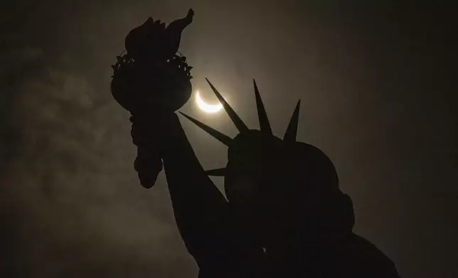 The moon partially covers the sun behind the Statue of Liberty during the a solar eclipse on the Liberty Island, Monday, April. 8, 2024, in New York. (AP Photo/Yuki Iwamura)