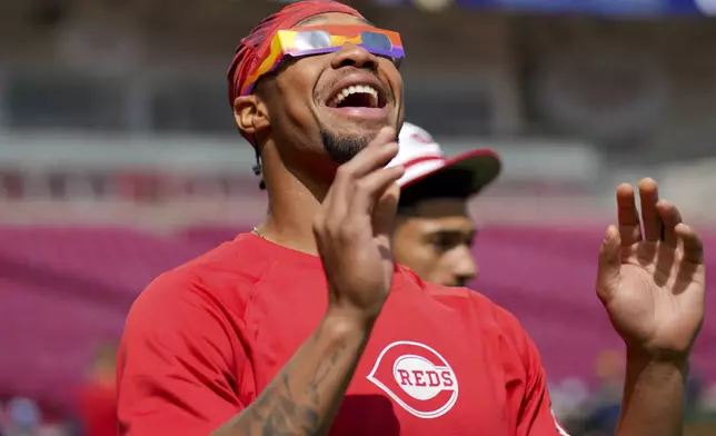 Cincinnati Reds' Will Benson reacts to the sun during a solar eclipse before a baseball game against the Milwaukee Brewers in Cincinnati, Monday, April 8, 2024. (AP Photo/Aaron Doster)