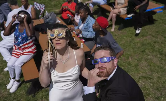 Samantha Palmer, left, and Gerald Lester watch a total solar eclipse before getting married during the event, Monday, April 8, 2024, in Trenton, Ohio. (AP Photo/Joshua A. Bickel)