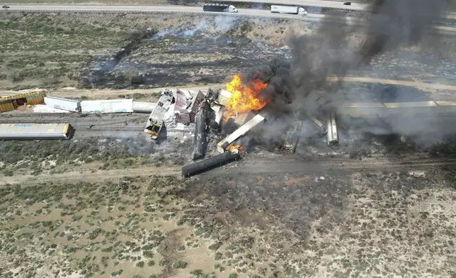 In this photo provided by David Yellowhorse, a freight train carrying fuel derailed and caught fire, Friday, April 26, 2024, east of Lupton, Ariz., near the New Mexico-Arizona state line. Authorities closed Interstate 40 in both directions in the area, directing trucks and motorists to alternate routes. (David Yellowhorse via AP)