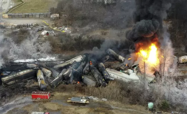 FILE - Portions of a Norfolk Southern freight train that derailed the night before burn in East Palestine, Ohio, Feb. 4, 2023. On Tuesday, April 9, 2024, Norfolk Southern has agreed to pay $600 million in a class-action lawsuit settlement related to a fiery train derailment in February 2023 in eastern Ohio. (AP Photo/Gene J. Puskar, File)