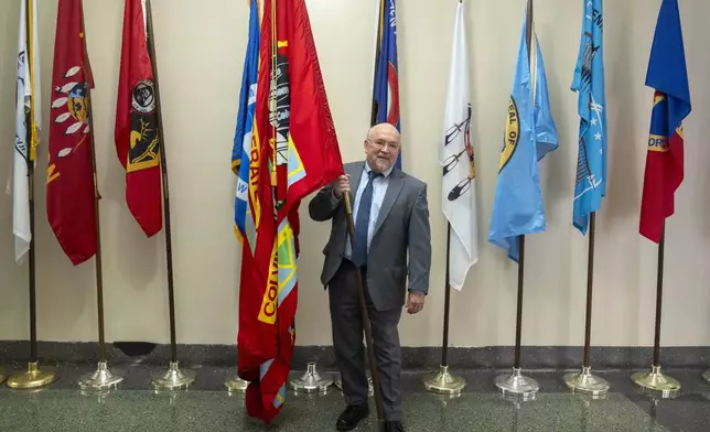 Tracy Toulou, the outgoing Director of the Office of Tribal Justice, holds the flag of the Colville Confederated Tribes, his tribal affiliation, alongside flags of tribal nations at the Department of Justice, Thursday, March 14, 2024, in Washington. For more than two decades, Toulou has confronted the serious public safety challenges facing Indian Country by working to expand the power of tribal justice systems. Today, tribal law enforcement finally has a seat at the table when federal authorities coordinate with state and local police, according to the Justice Department’s point person on Native American tribes. (AP Photo/Mark Schiefelbein)