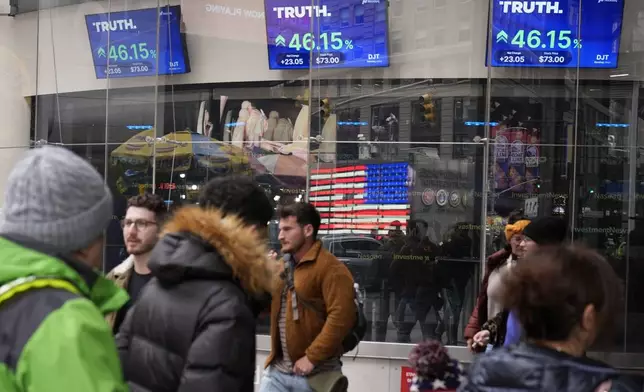 FILE - Pedestrians walk past the Nasdaq building Tuesday, March 26, 2024, in New York with the stock price of Trump Media &amp; Technology Group Corp., displayed on screens. (AP Photo/Frank Franklin II, File)