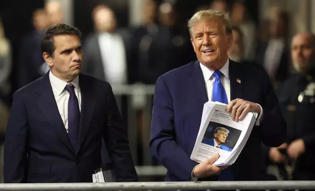 Former President Donald Trump holds up news clippings as he speaks following his trial at Manhattan criminal court in New York on Thursday, April 18, 2024. Attorney Todd Blanche listens at left. (Brendan McDermid/Pool Photo via AP)