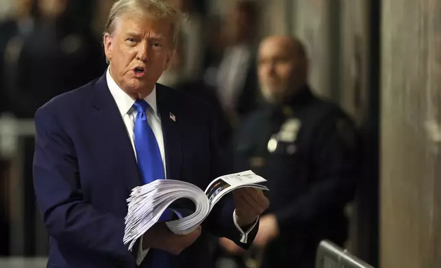 Former President Donald Trump speaks with the media while holding news clippings following his trial at Manhattan criminal court in New York on Thursday, April 18, 2024. (Brendan McDermid/Pool Photo via AP)