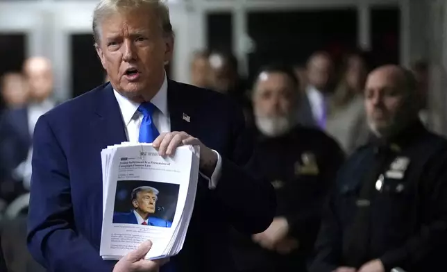 Former President Donald Trump holds up news clippings as he speaks following his trial at Manhattan criminal court in New York on Thursday, April 18, 2024. (Timothy A. Clary/Pool Photo via AP)