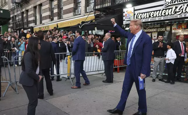 Former president Donald Trump, motions to a crowd after visiting a bodega, Tuesday, April 16, 2024, who's owner was attacked last year in New York. Fresh from a Manhattan courtroom, Donald Trump visited a New York bodega where a man was stabbed to death, a stark pivot for the former president as he juggles being a criminal defendant and the Republican challenger intent on blaming President Joe Biden for crime. Alba's attorney, Rich Cardinale, second from left, and Fransisco Marte, president of the Bodega Association, looked on. (AP Photo/Yuki Iwamura)