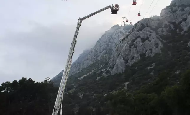 A rescue team work with passengers of a cable car transportation systems outside Antalya, southern Turkey, April, Friday 12, 2024. A cable car disaster in southern Turkey left one person dead and seven injured over the busy Eid al-Fitr public holiday on Friday, local media reported. (IHA via AP)
