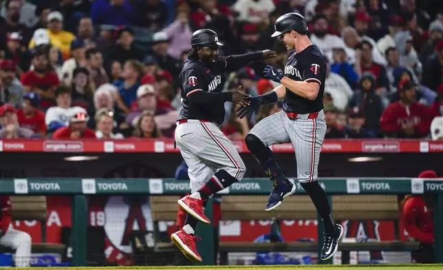 Minnesota Twins' Max Kepler, right, celebrates his solo home run with third base coach Tommy Watkins during the sixth inning of the team's baseball game against the Los Angeles Angels, Saturday, April 27, 2024, in Anaheim, Calif. (AP Photo/Ryan Sun)