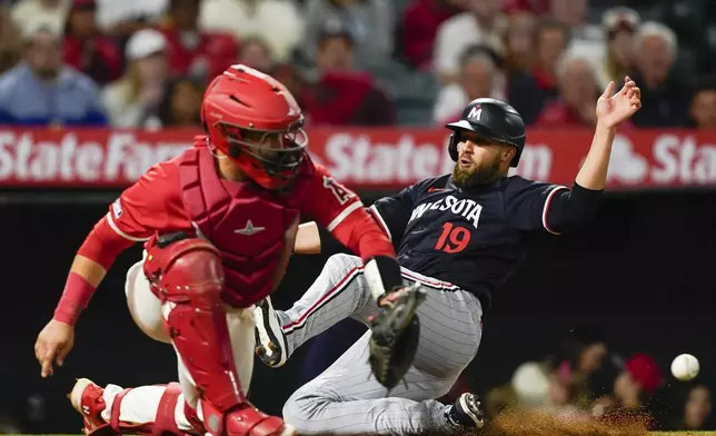 Minnesota Twins' Alex Kirilloff, right, slides home past Los Angeles Angels catcher Matt Thaiss to score on a double by Edouard Julien during the seventh inning of a baseball game Saturday, April 27, 2024, in Anaheim, Calif. (AP Photo/Ryan Sun)
