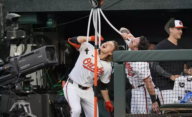 Baltimore Orioles' Gunnar Henderson (2) and James McCann (27) drink from the team's Homer Hydration Station after scoring on Henderson's home run against the Minnesota Twins during the second inning of a baseball game Tuesday, April 16, 2024, in Baltimore. (AP Photo/Jess Rapfogel)