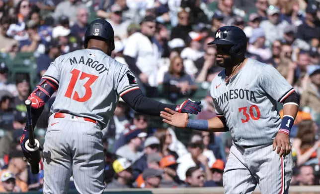 Minnesota Twins' Carlos Santana (30) celebrates scoring with Manuel Margot (13) against the Detroit Tigers in the 11th inning during the first baseball game of a doubleheader, Saturday, April 13, 2024, in Detroit. (AP Photo/Paul Sancya)