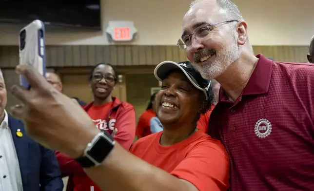 Volkswagen automobile plant employee LaShawn Hawthorne, center left, takes picture with UAW president Shawn Fain after workers voted to join the union Friday, April 19, 2024, in Chattanooga, Tenn. (AP Photo/George Walker IV)