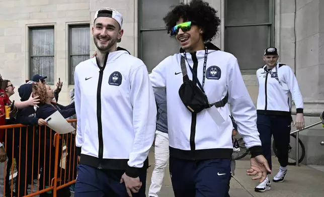 UConn's Alex Karaban, left, and Jayden Ross, right, smile as they board a bus for a parade to celebrate the team's NCAA college basketball championship, Saturday, April 13, 2024, in Hartford, Conn. (AP Photo/Jessica Hill)