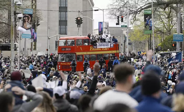 Fans surround a double-decker bus carrying the UConn men's basketball team during a parade to celebrate the team's NCAA college basketball championship, Saturday, April 13, 2024, in Hartford, Conn. (AP Photo/Jessica Hill)