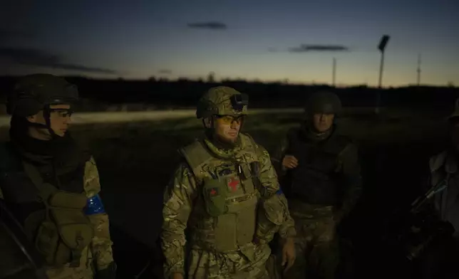 Oleksii Yukov and his team members wait for colleagues to offload the bodies of Russian soldiers they've collected from the frontline in the Sloviansk region, Ukraine, Tuesday, Oct. 24, 2023. “Sometimes I just want to scream. To yell. Because you realize what madness and pain it is,” Yukov says. “I understand that I do not have enough life to finish this work of searching for the dead.” (AP Photo/Bram Janssen)