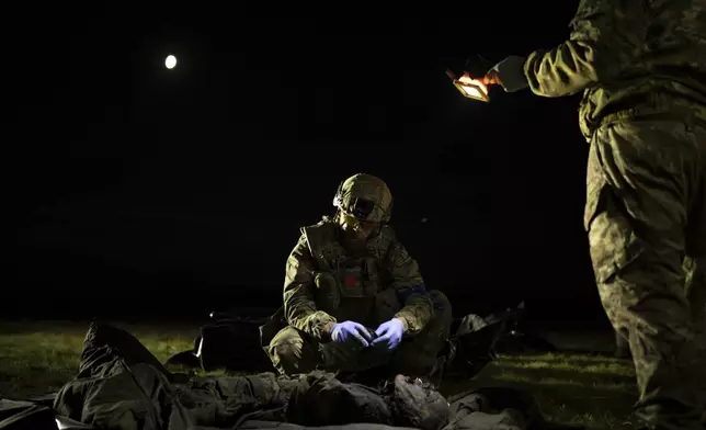 Oleksii Yukov examines the body of a Russian soldier he collected on the frontline in the Sloviansk region, Ukraine, Tuesday, Oct. 24, 2023. Yukov understands that for people far away, war is geopolitics, death can be counted in numbers, and money matters more than men. But he knows better. “War has one face,” he said. “Death and stupidity and horror.” (AP Photo/Bram Janssen)