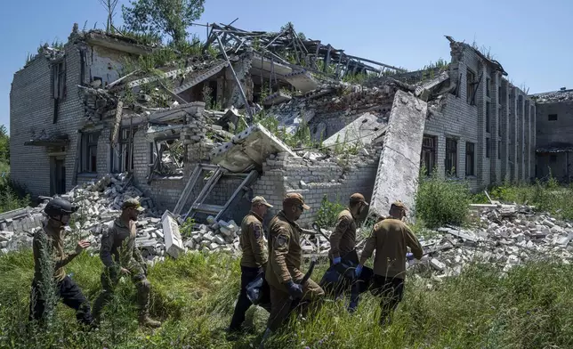 FILE - Oleksii Yukov, second right, and other body collectors carry the body of a Russian soldier that was exhumed from a shell crater in front of destroyed school in Virnopillia, Ukraine, Thursday, July 6, 2023. (AP Photo/Evgeniy Maloletka, File)