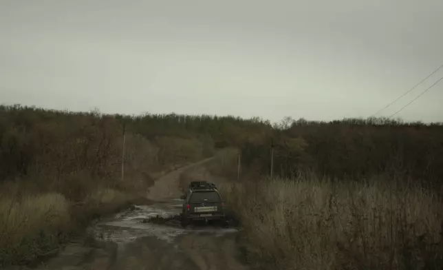 Oleksii Yukov and his team drive through a pothole on a road towards the frontline in Sloviansk region, Ukraine, Wednesday, Oct. 25, 2023. The 38-year-old martial arts instructor who leads a team of volunteer body collectors in Ukraine says he's collected over 1,000 bodies since the full-scale invasion began two years ago, more than 580 of them Russians. (AP Photo/Bram Janssen)