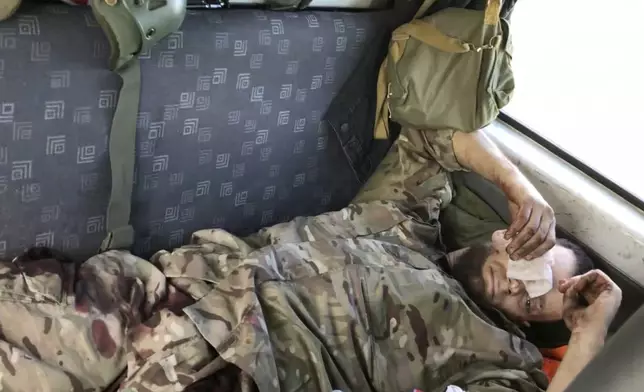 In this image from video provided by Platsdarm, the group of body collectors led by Oleksii Yukov, Yukov lies in a vehicle after he stepped on a mine in Dovhenke, Ukraine, on Sept. 19, 2022. I was like, 'OK. Legs are in place.' But suddenly, I can't see with my eye. There's no eye." (Platsdarm via AP)