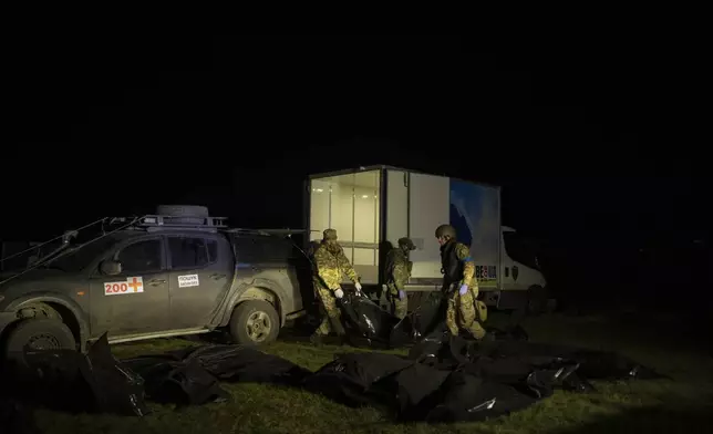 Team members of Oleksii Yukov offload the bodies of Russian soldiers they've collected from the frontline from their pickup truck in the Sloviansk region, Ukraine, Tuesday, Oct. 24, 2023. More than half a million people have been killed or seriously injured in two years of war in Ukraine, according to Western intelligence estimates -- a human toll not seen in Europe since World War II. The question of who prevails is being increasingly shaped by which side can tolerate higher losses. (AP Photo/Bram Janssen)