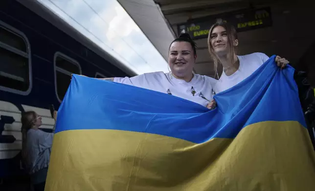 Ukrainian rapper alyona alyona, left, and singer Jerry Heil hold the Ukrainian flag as they pose for the media before departing from the main train station in Kyiv, Ukraine, Thursday, April 25, 2024. Ukraine’s entrants in the pan-continental music competition, the female duo of rapper alyona alyona and singer Jerry Heil set off from Kyiv for the competition on Thursday. In wartime, that means a long train journey to Poland, from where they will travel on to next month’s competition in Malmö, Sweden. (AP Photo/Francisco Seco)