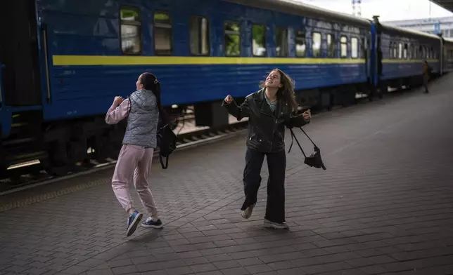 Two girls dance as Ukraine's song entrance in the Eurovision contest is played at the main train station, in Kyiv, Ukraine, Thursday, April 25, 2024. Ukraine’s entrants in the pan-continental music competition, the female duo of rapper alyona alyona and singer Jerry Heil set off from Kyiv for the competition on Thursday. In wartime, that means a long train journey to Poland, from where they will travel on to next month’s competition in Malmö, Sweden. (AP Photo/Francisco Seco)