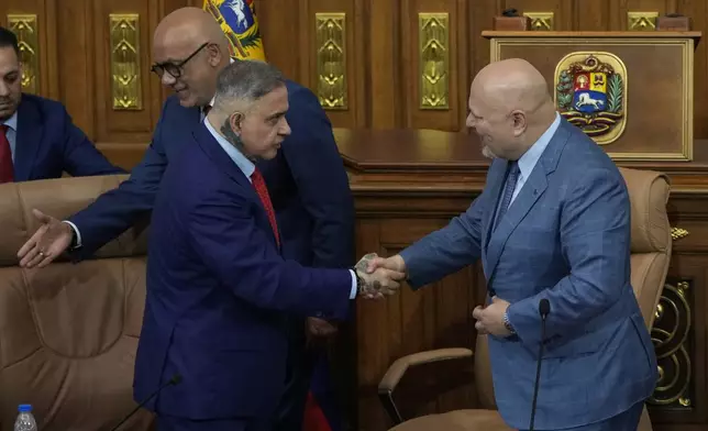 Karim Khan, chief prosecutor of the International Criminal Court, right, shakes hands with Venezuelan General Attorney Tarek William Saab after a meeting at the National Assembly in Caracas, Venezuela, Monday, April 22, 2024. Behind is Jorge Rodriguez, National Assembly president. (AP Photo/Ariana Cubillos)