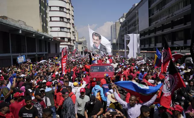 FILE - Venezuelan President Nicolas Maduro waving a banner emblazoned with an image of himself is accompanied by supporters as he is driven to the electoral council headquarters to register his candidacy for a third term, in Caracas, Venezuela, March 25, 2024. (AP Photo/Matias Delacroix, File)