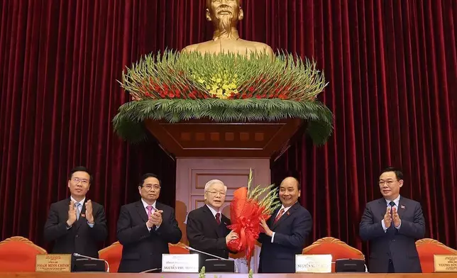 FILE - Vietnam Communist party General Secretary Nguyen Phu Trong, center left, is presented with a bouquet by Prime Minister Nguyen Xuan Phuc, center right, in Hanoi, Vietnam, Sunday, Jan. 31, 2021. Vietnamese state media outlet VN Express reports that the head of Vietnam’s Parliament, Vuong Dinh Hue, has resigned. He is the latest member of senior government to leave office amid an ongoing anti-corruption campaign. (Le Tri Dung/VNA via AP, File)