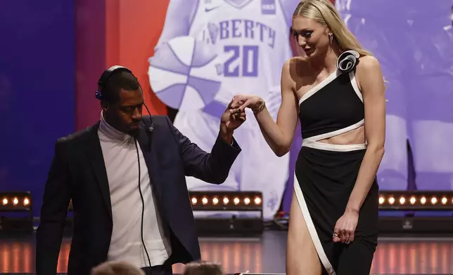 Stanford's Cameron Brink, right, is escorted off the state after being selected second overall by the Los Angeles Sparks during the first round of the WNBA basketball draft, Monday, April 15, 2024, in New York. (AP Photo/Adam Hunger)