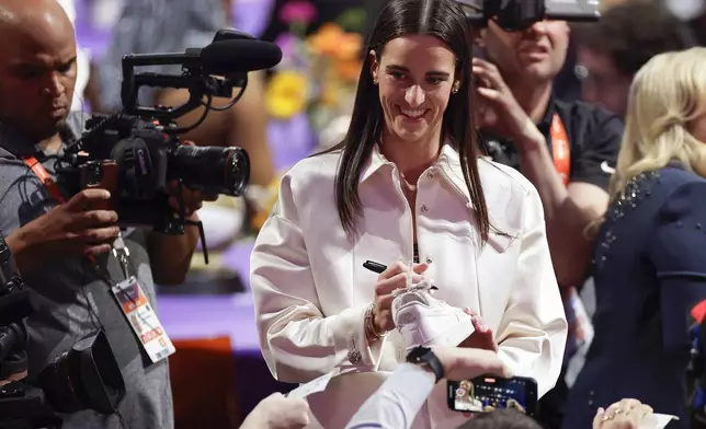 Iowa's Caitlyn Clark signs autographs before the start of the WNBA basketball draft, Monday, April 15, 2024, in New York. (AP Photo/Adam Hunger)