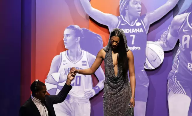 LSU's Angel Reese, right, is helped off the stage after being selected seventh overall by the Chicago Sky during the first round of the WNBA basketball draft on Monday, April 15, 2024, in New York. (AP Photo/Adam Hunger)