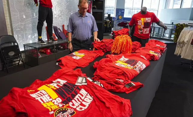 A customer looks over Caitlin Clark merchandise in the Indiana Fever team store in Indianapolis, Tuesday, April 16, 2024. The Fever selected Clark Clark as the No. 1 overall pick in the WNBA basketball draft. (AP Photo/Michael Conroy)