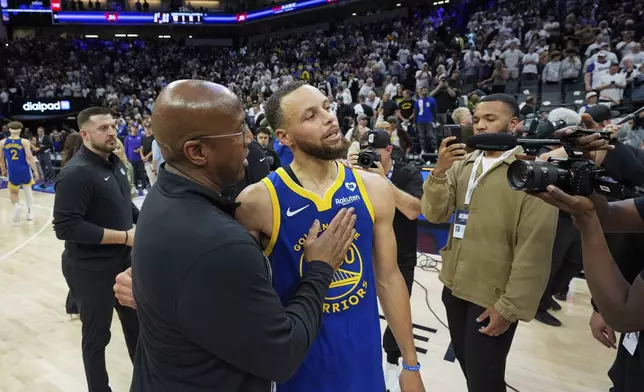 Sacramento Kings coach Mike Brown, left, talks with Golden State Warriors guard Stephen Curry after an NBA basketball play-in tournament game Tuesday, April 16, 2024, in Sacramento, Calif. The Kings won 118-94. (AP Photo/Godofredo A. Vásquez)