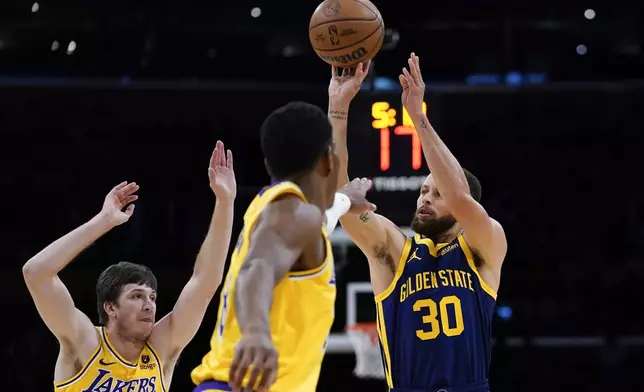 Golden State Warriors guard Stephen Curry, right, shoots against Los Angeles Lakers guard Austin Reaves, left, and forward Rui Hachimura during the first half of an NBA basketball game Tuesday, April 9, 2024, in Los Angeles. (AP Photo/Ryan Sun)