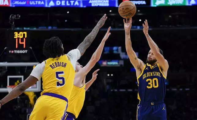 Golden State Warriors guard Stephen Curry, right, shoots againstLos Angeles Lakers forward Cam Reddish, left, and guard Austin Reaves during the first half of an NBA basketball game Tuesday, April 9, 2024, in Los Angeles. (AP Photo/Ryan Sun)