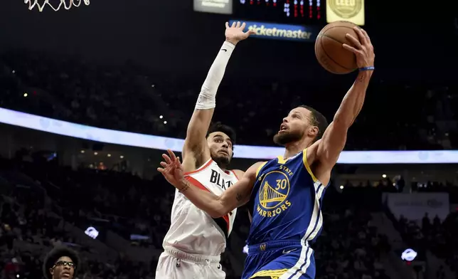 Golden State Warriors guard Stephen Curry, right, drives to the basket against Portland Trail Blazers forward Justin Minaya, center left, during the first half of an NBA basketball game in Portland, Ore., Thursday, April 11, 2024. (AP Photo/Steve Dykes)