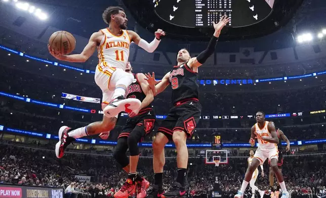 Atlanta Hawks guard Trae Young, left, looks to pass against Chicago Bulls guard Alex Caruso and center Nikola Vucevic, right, during the first half of an NBA basketball play-in tournament game in Chicago, Wednesday, April 17, 2024. (AP Photo/Nam Y. Huh)