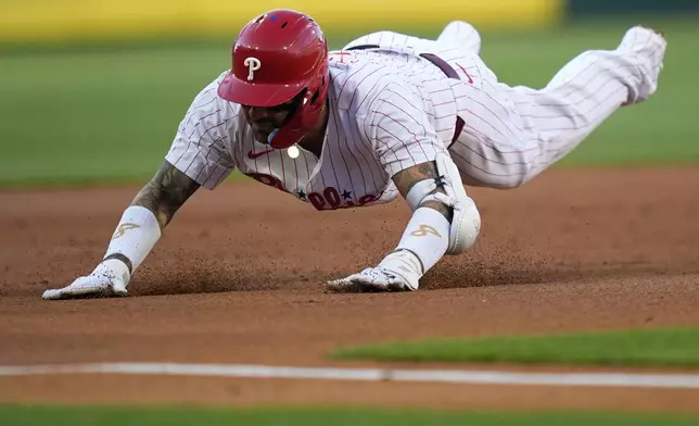 Philadelphia Phillies' Nick Castellanos dives towards third base after hitting a triple during the second inning of a baseball game against the Chicago White Sox, Saturday, April 20, 2024, in Philadelphia. (AP Photo/Matt Slocum)