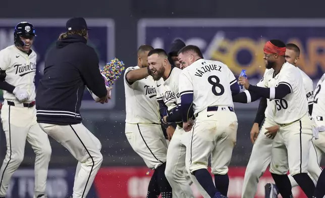 Minnesota Twins Alex Kirilloff (19) is surrounded by teammates in celebration after he drove in the winning run against the Chicago White Sox during the ninth inning of a baseball game Tuesday, April 23, 2024, in Minneapolis. (AP Photo/Stacy Bengs)