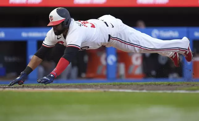 Minnesota Twins' Carlos Santana dives to score against the Chicago White Sox during the second inning of a baseball game Wednesday, April 24, 2024, in Minneapolis. (AP Photo/Abbie Parr)