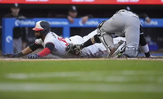 Minnesota Twins' Carlos Santana, left, beats the tag by Chicago White Sox catcher Korey Lee to score during the second inning of a baseball game Wednesday, April 24, 2024, in Minneapolis. (AP Photo/Abbie Parr)