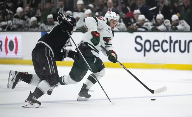 Minnesota Wild left wing Kirill Kaprizov, right, controls the puck past Los Angeles Kings defenseman Mikey Anderson, left, during the first period of an NHL hockey game, Monday, April 15, 2024, in Los Angeles. (AP Photo/Kyusung Gong)