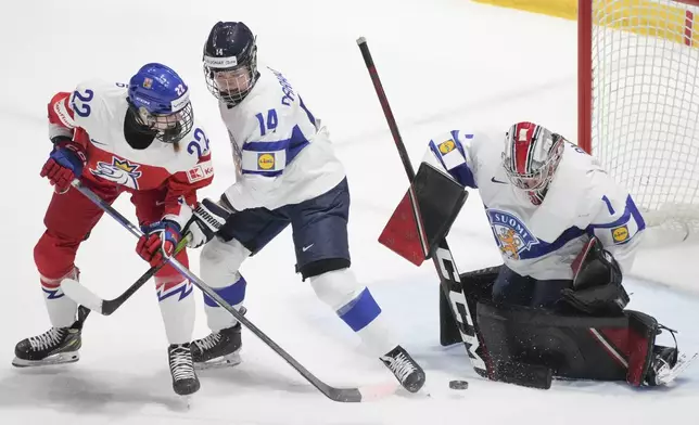 Finland goaltender Sanni Ahola (1) makes a save against Czechia's Tereza Plosova (22) as Finland's Krista Parkkonen (14) defends during first-period bronze medal hockey game action at the women's world hockey championships in Utica, N.Y., Sunday, April 14, 2024. (Christinne Muschi/The Canadian Press via AP)