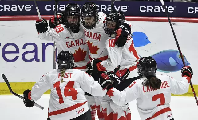 Canada forward Marie-Philip Poulin, top left, celebrates with defensewoman Renata Fast (14), forward Brianne Jenner (19), forward Sarah Fillier (10) and defensewoman Jocelyne Larocque after scoring against the United States during the third period in the final at the IIHF Women's World Hockey Championships in Utica, N.Y., Sunday, April 14, 2024. (AP Photo/Adrian Kraus)