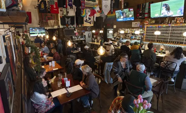 Customers eat and watch college women's lacrosse and beach volleyball matches on big-screen TVs at The Sports Bra sports bar on Wednesday, April 24, 2024, in Portland, Ore. (AP Photo/Jenny Kane)