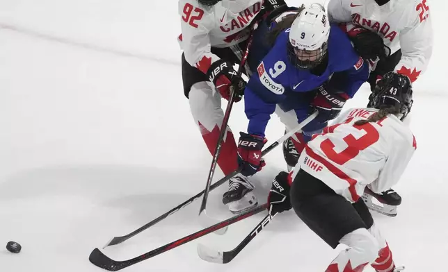 Canada's Danielle Serdachny (92), Jaime Bourbonnais (25) and Kristin O'Neill (43) battle with United States' Kirsten Simms (9) during the second period of a hockey game at the IIHF Women's World Hockey Championship in Utica, N.Y., Monday, April 8, 2024. (Christinne Muschi/The Canadian Press via AP)